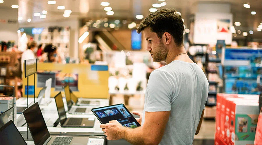 Technician at PayMore Sand Lake checking a laptop before resale